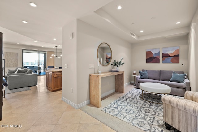 tiled living room featuring an inviting chandelier and a raised ceiling