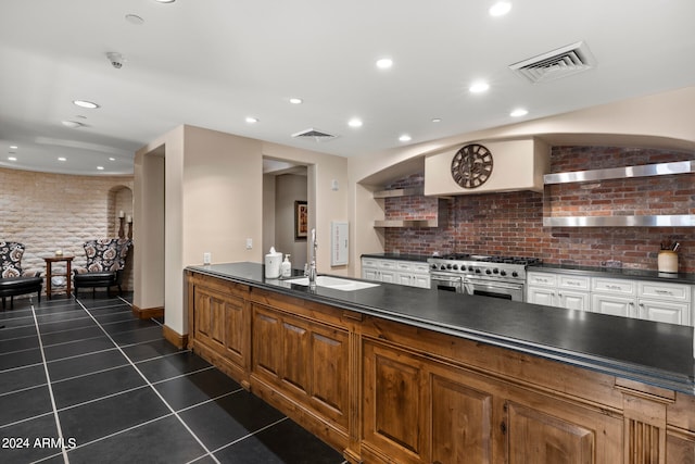 kitchen with double oven range, dark tile flooring, tasteful backsplash, and sink