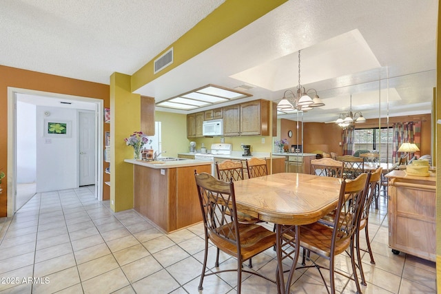 dining space with a notable chandelier, light tile patterned flooring, visible vents, and a textured ceiling