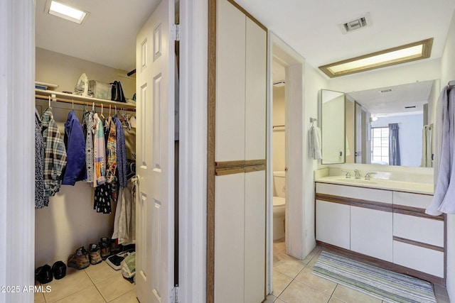 full bathroom featuring vanity, visible vents, tile patterned flooring, a spacious closet, and toilet