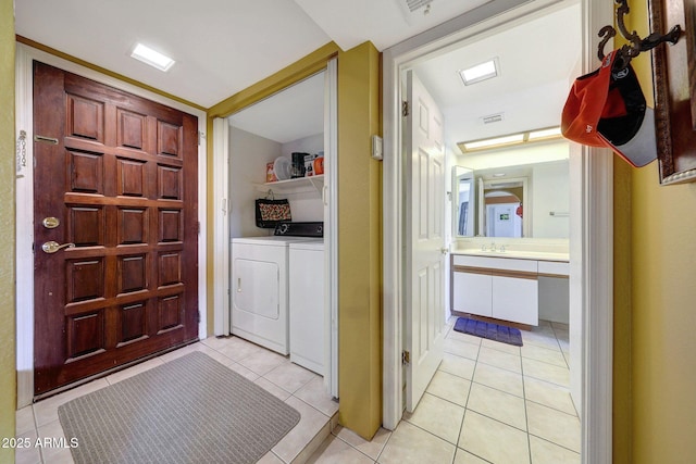 foyer entrance with light tile patterned flooring, visible vents, and separate washer and dryer