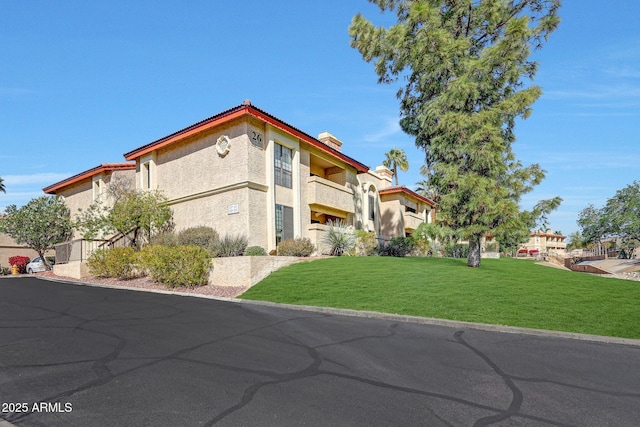 view of side of property with stucco siding, a chimney, and a yard