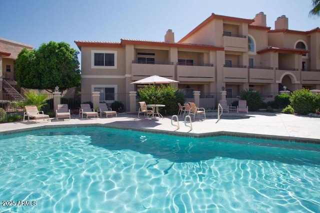 community pool with a patio area and fence