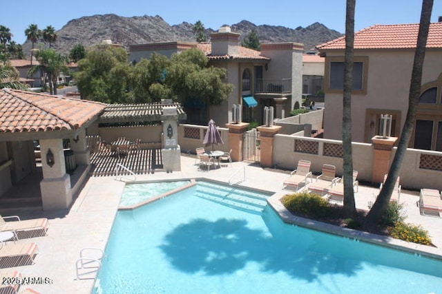 community pool featuring a patio area, a mountain view, and fence