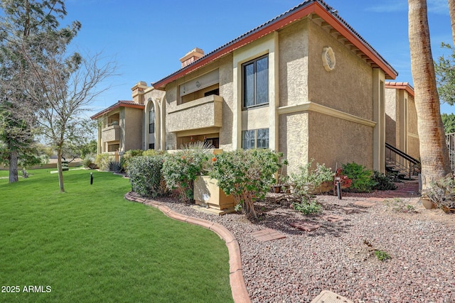 exterior space with a yard, a chimney, and stucco siding