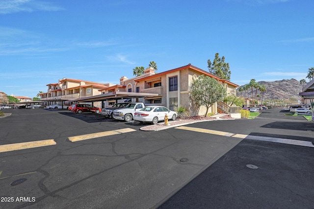 partially covered parking lot featuring a mountain view and a residential view