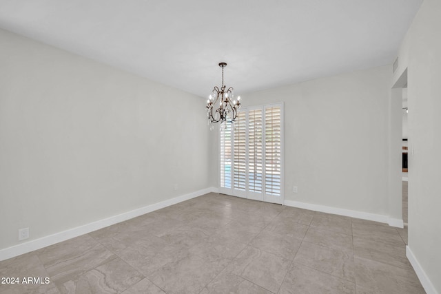 unfurnished room featuring a chandelier