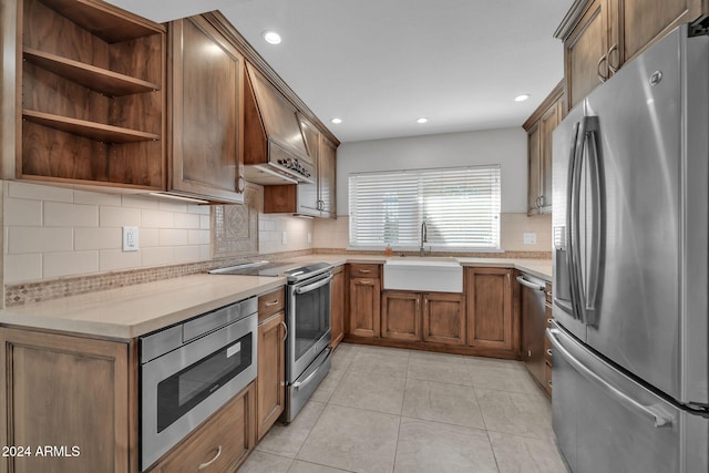 kitchen with sink, tasteful backsplash, light tile patterned floors, custom range hood, and appliances with stainless steel finishes