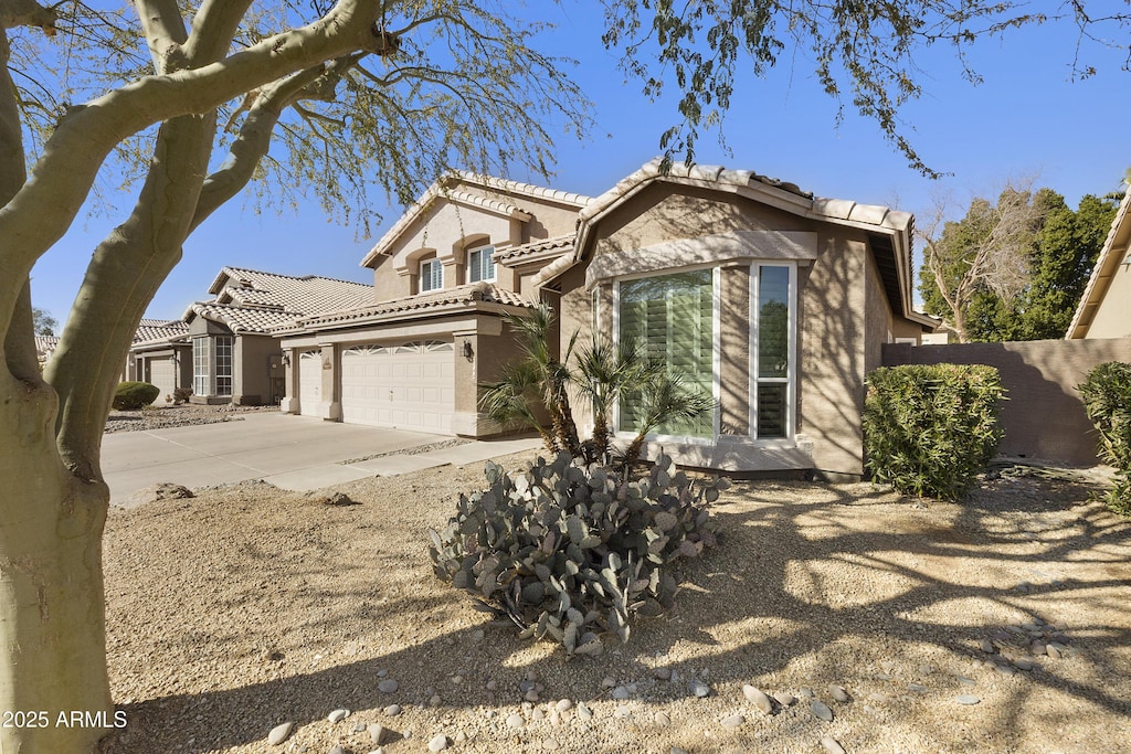 view of front of property with driveway, a garage, fence, and stucco siding
