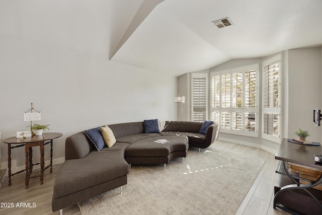 living room featuring vaulted ceiling, baseboards, visible vents, and light wood-style floors