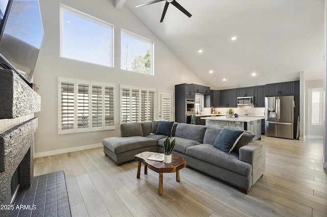 living room featuring a fireplace with flush hearth, a wealth of natural light, light wood-style floors, and baseboards