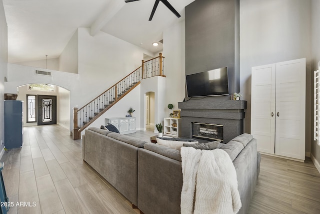 living room featuring arched walkways, stairway, and light wood finished floors