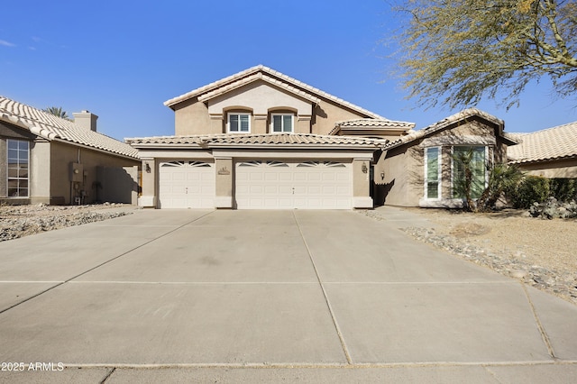 mediterranean / spanish-style house featuring a garage, concrete driveway, a tile roof, and stucco siding