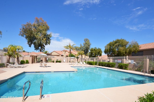 community pool featuring a patio area, fence, and a residential view