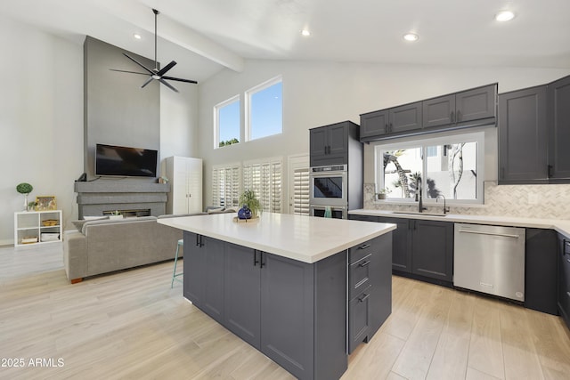 kitchen with appliances with stainless steel finishes, open floor plan, light countertops, and a kitchen island