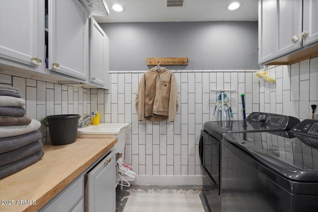 washroom with washer and dryer, cabinet space, tile walls, and recessed lighting