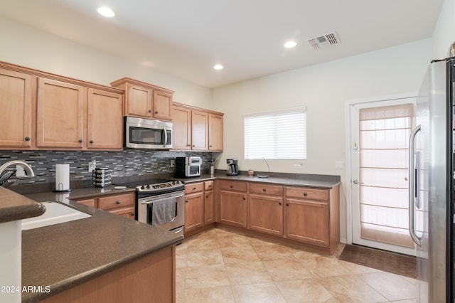 kitchen with appliances with stainless steel finishes, tasteful backsplash, light tile patterned floors, and sink