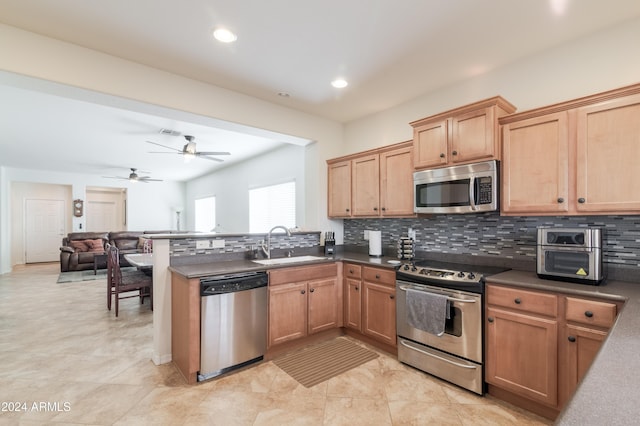 kitchen featuring ceiling fan, sink, stainless steel appliances, backsplash, and kitchen peninsula