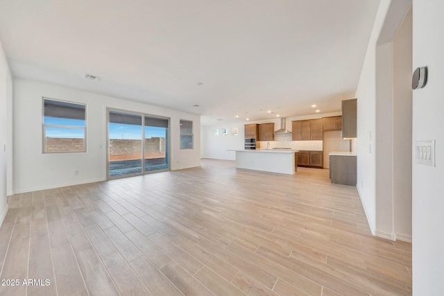 unfurnished living room with light wood-style flooring, recessed lighting, visible vents, and baseboards