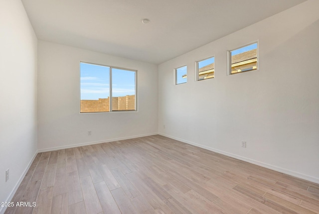 unfurnished room with light wood-style flooring and baseboards