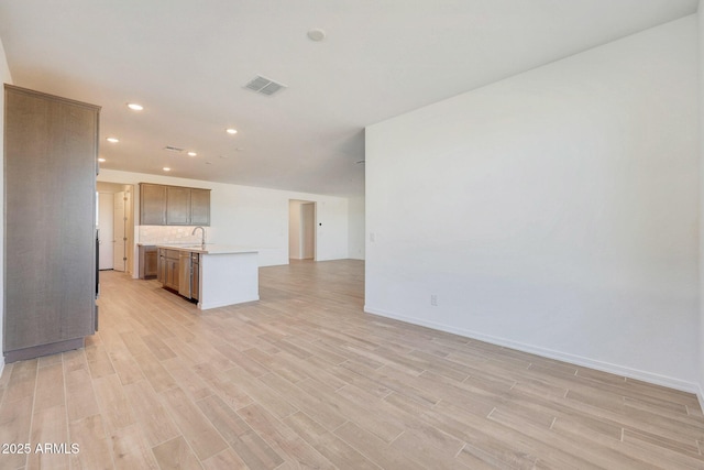 kitchen with visible vents, light wood-style flooring, a sink, light countertops, and open floor plan