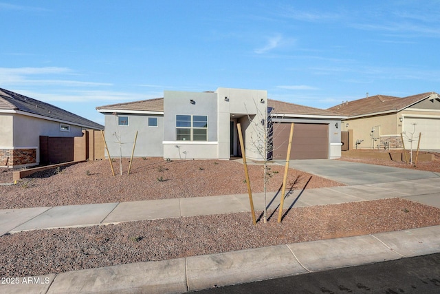 view of front facade with an attached garage, fence, driveway, and stucco siding