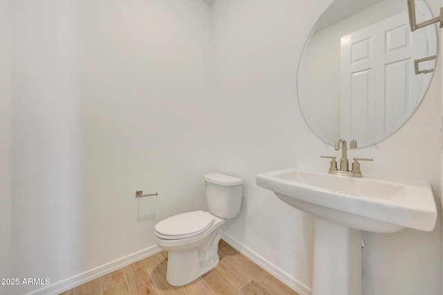 half bath featuring toilet, baseboards, and wood finished floors