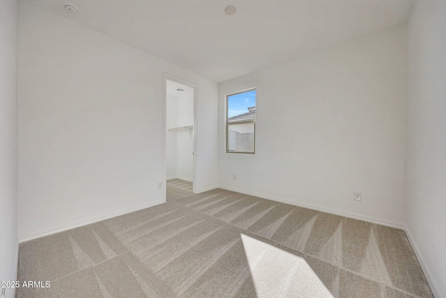 unfurnished room featuring stairs, light colored carpet, and baseboards