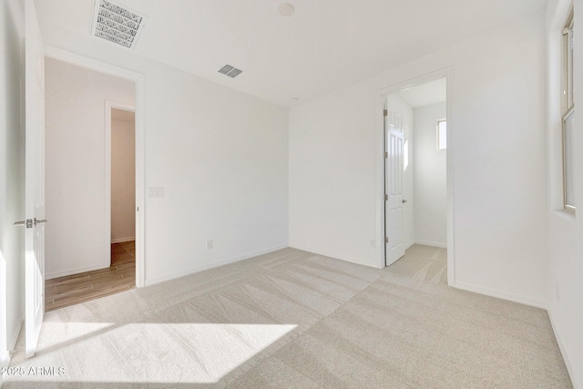 unfurnished room featuring visible vents and light carpet