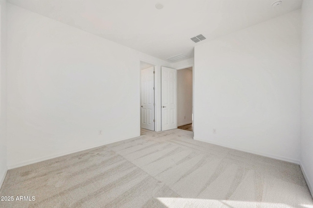 spare room with light colored carpet, visible vents, and baseboards