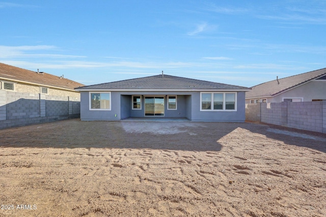 back of house featuring stucco siding and a fenced backyard