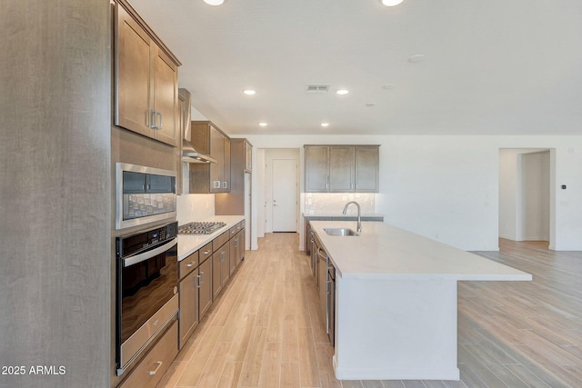 kitchen featuring a sink, stainless steel appliances, visible vents, and light wood finished floors