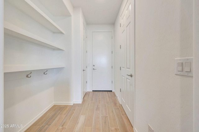 corridor featuring light wood-type flooring and baseboards