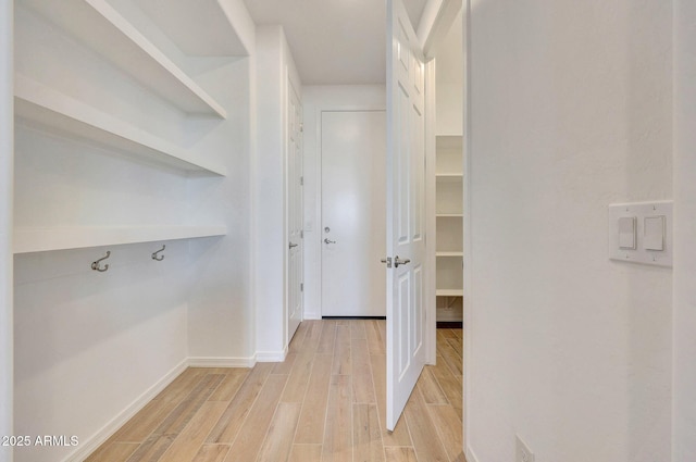 hallway featuring light wood-type flooring and baseboards