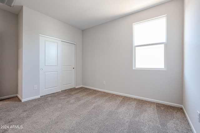 unfurnished bedroom featuring carpet, multiple windows, and a closet