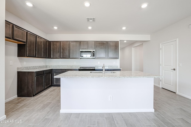 kitchen featuring appliances with stainless steel finishes, light hardwood / wood-style flooring, a kitchen island with sink, and sink