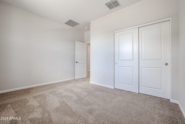 unfurnished bedroom featuring light carpet and a closet