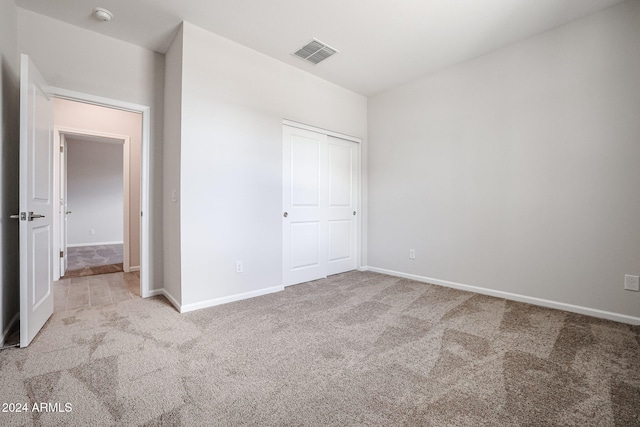 unfurnished bedroom featuring a closet and light colored carpet