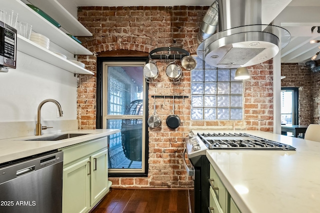 kitchen featuring a sink, appliances with stainless steel finishes, green cabinets, and brick wall