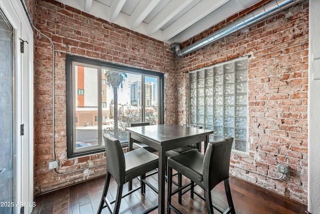 dining area featuring beam ceiling, brick wall, and dark wood-style flooring