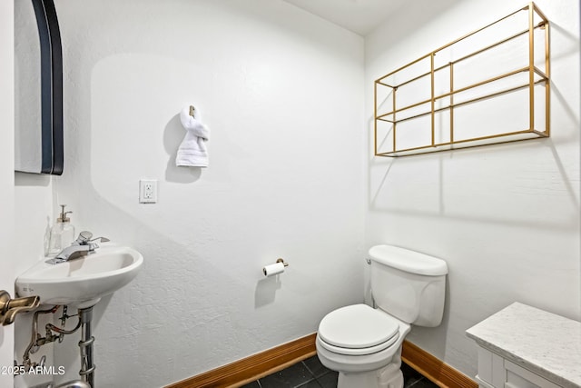 half bathroom with tile patterned flooring, toilet, baseboards, and a sink