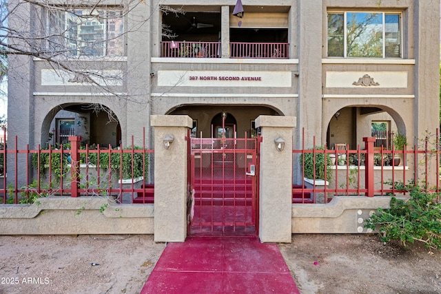 doorway to property featuring stucco siding and fence