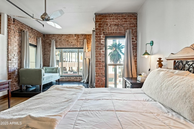 bedroom with brick wall, wood finished floors, and access to outside