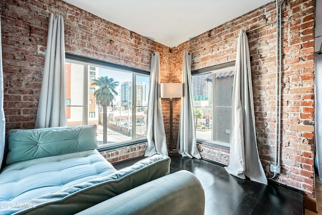 sitting room featuring wood finished floors and brick wall