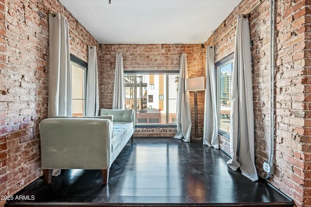 unfurnished room featuring brick wall and dark wood-style flooring