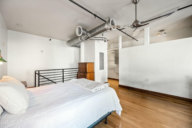 bedroom featuring electric panel, baseboards, and wood finished floors