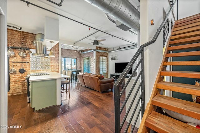 interior space with hardwood / wood-style floors, rail lighting, brick wall, and ceiling fan