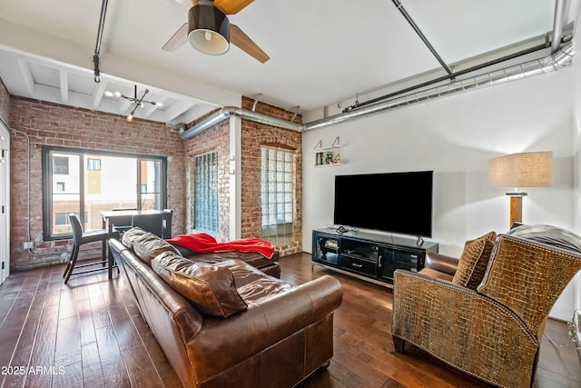 living area featuring beamed ceiling, ceiling fan with notable chandelier, brick wall, and dark wood-type flooring