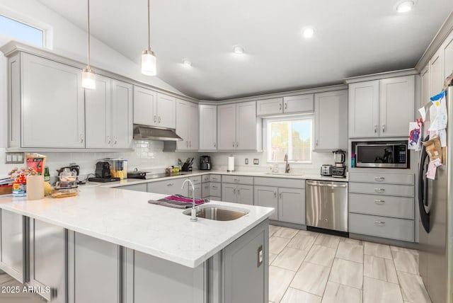 kitchen featuring appliances with stainless steel finishes, a peninsula, under cabinet range hood, pendant lighting, and a sink