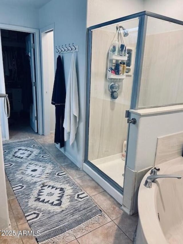 full bathroom with a stall shower, a walk in closet, and tile patterned floors